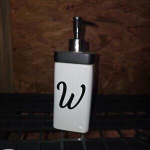 Ceramic soap dispenser with "W" on it. White and Black